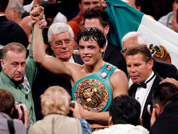 FILE - Julio Cesar Chavez, Jr., center, of Mexico poses with his belt along with his father Julio Cesar Chavez, Sr., right, and referee Jack Reiss after defeating Sebastian Zbik of Germany after their WBC World Middleweight title boxing match, in Los Angeles, June 4, 2011. (AP Photo/Richard Vogel, File)