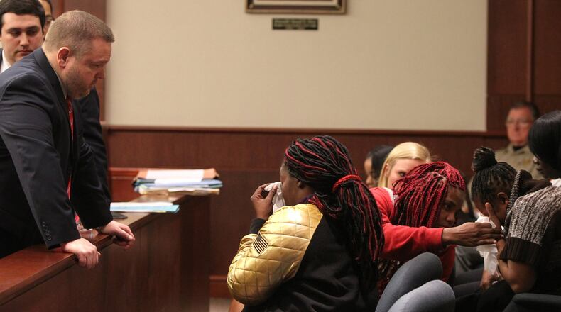 District Attorney Brian Fortner (left) looks over a wall separating the jury box from the rest of the court to ask Hyesha Bryant (center) whether the group needs anything while Melissa Alford (right, striped sweater) weeps. Several victims of the hate crime were seated in the jury box for the sentencing. (HENRY TAYLOR / HENRY.TAYLOR@AJC.COM)