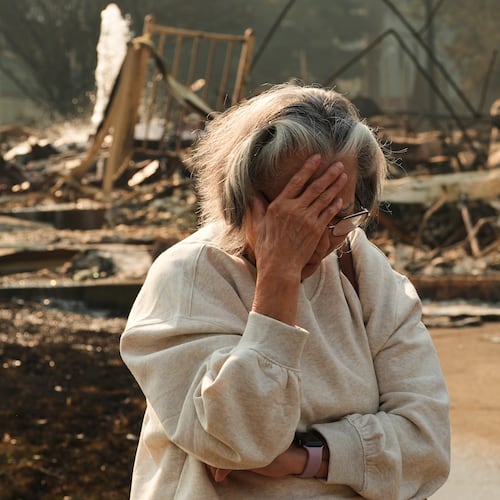 Miriam Sim, 76, reacts while talking about her neighborhood largely burning to the ground after a wildfire hit the northern part of Spokane, Wash., Monday, Aug. 3, 2026. (AP Photo/Lindsey Wasson)