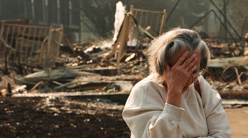 Miriam Sim, 76, reacts while talking about her neighborhood largely burning to the ground after a wildfire hit the northern part of Spokane, Wash., Monday, Aug. 3, 2026. (AP Photo/Lindsey Wasson)
