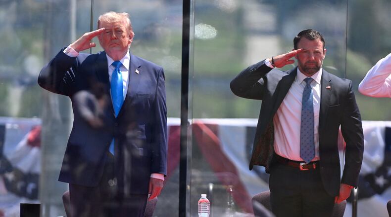 President Donald Trump, left, and Secretary of Homeland Security Markwayne Mullin, right, saluting at the start of the commencement ceremony at the U.S. Coast Guard Academy in New London, Conn., Wednesday, May 20, 2026. (AP Photo/Jessica Hill)