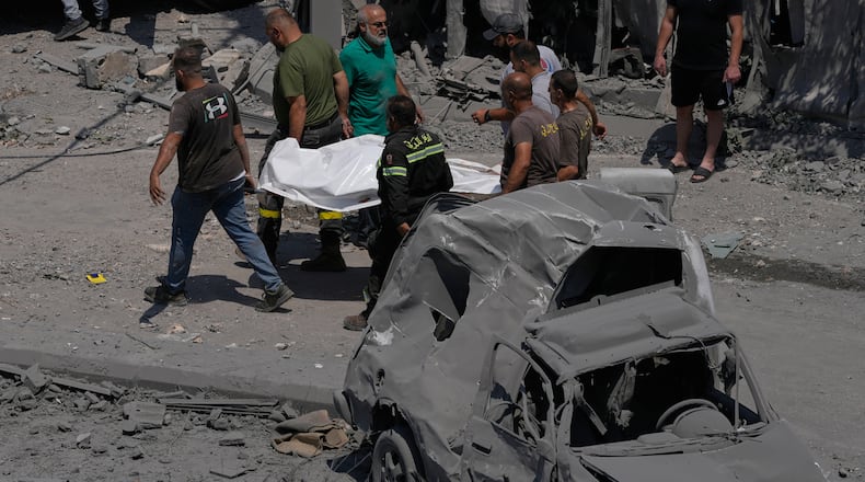 Rescue workers carry a plastic bag, containing the body of a person who was killed at a house that was hit by an Israeli airstrike in Deir al-Zahrani village, southern Lebanon, Saturday, Aug. 15, 2026. (AP Photo/Mohammed Zaatari)