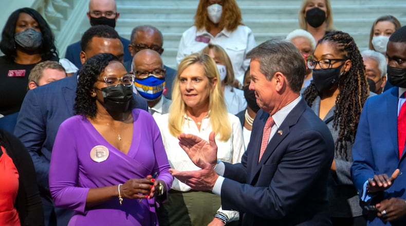 Wanda Cooper-Jones (left), mother of Ahmaud Arbery, stands with Gov. Brian Kemp after he signs House Bill 479, which overhauls Georgia's citizen's arrest law at the state Capitol Monday, May 10, 2021.   STEVE SCHAEFER FOR THE ATLANTA JOURNAL-CONSTITUTION