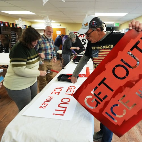 Wayne Rysdahl helps paint protest signs Wednesday, Jan. 28, 2026, in a church basement in Northglenn, Colo. (AP Photo/David Zalubowski)