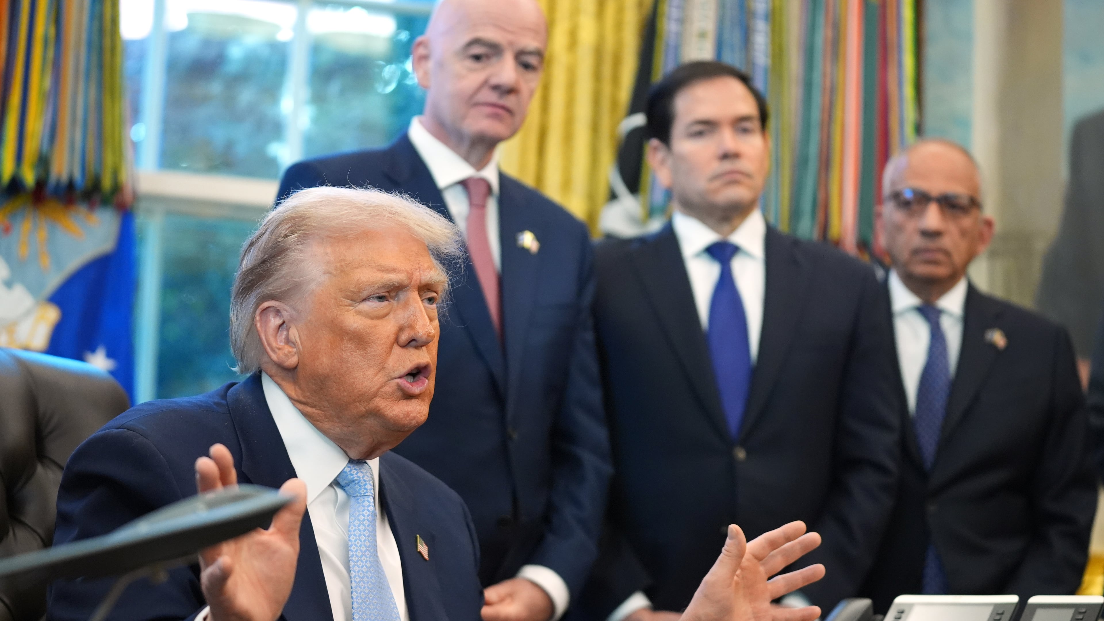 President Donald Trump answers questions from reporters during a meeting with the White House task force on the 2026 FIFA World Cup in the Oval Office of the White House, Monday, Nov. 17, 2025, in Washington, as FIFA President Gianni Infantino, Secretary of State Marco Rubio and FIFA senior adviser Carlos Cordeiro listen. (AP Photo/Evan Vucci)