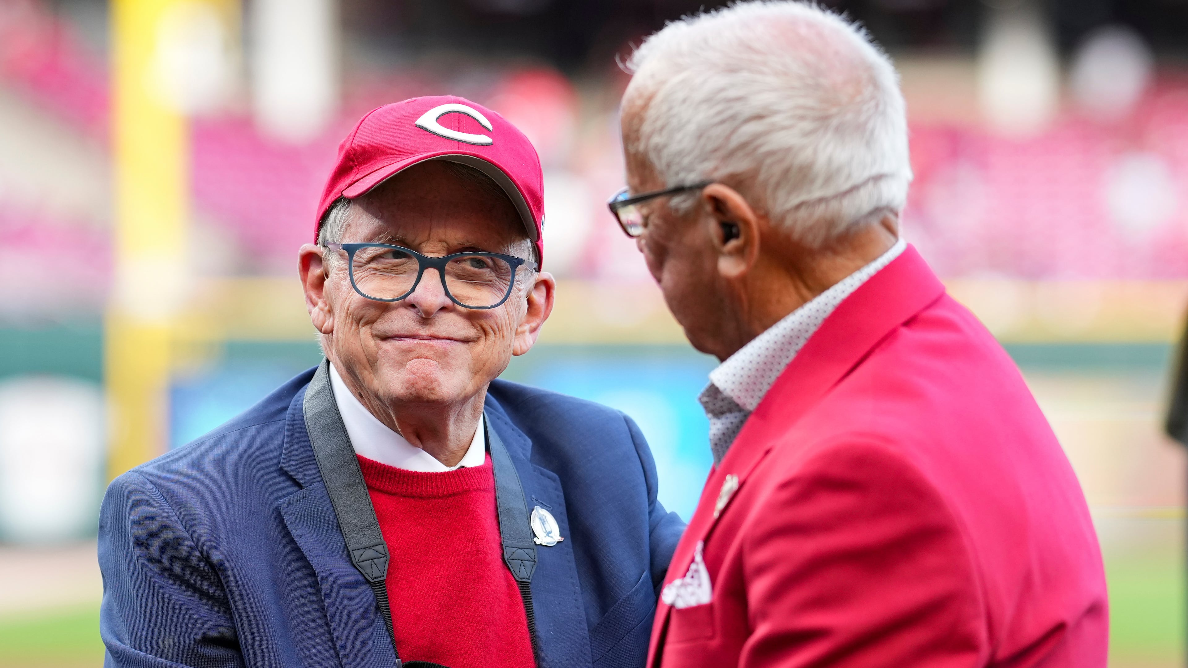 FILE - Hall of Fame broadcaster Marty Brennaman, right, speaks with Ohio Gov. Mike DeWine, left, during "Marty Brennaman Day" prior to a baseball game between the New York Mets and the Cincinnati Reds, Saturday, Sept. 6, 2025, in Cincinnati. (AP Photo/Jeff Dean, File)