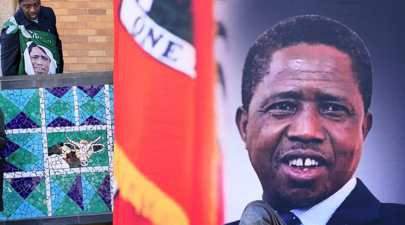 FILE -A supporter arrives for a Mass for former Zambian President Edgar Lungu, shown in a banner at right, at the Cathedral of Christ the King in Johannesburg, South Africa, June 25, 2025. (AP Photo/Themba Hadebe, File)