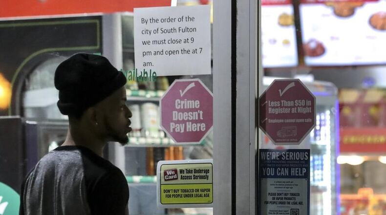 A sign lets customers know about the city of South Fulton’s curfew at 3515 Cascade Road on Thursday, March 19, 2020. JOHN SPINK/JSPINK@AJC.COM