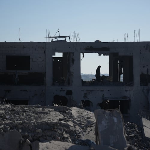A Palestinian woman inspects a destroyed building following an Israeli airstrike in Deir al-Balah, central Gaza Strip, Sunday, July 19, 2026. (AP Photo/Abdel Kareem Hana)