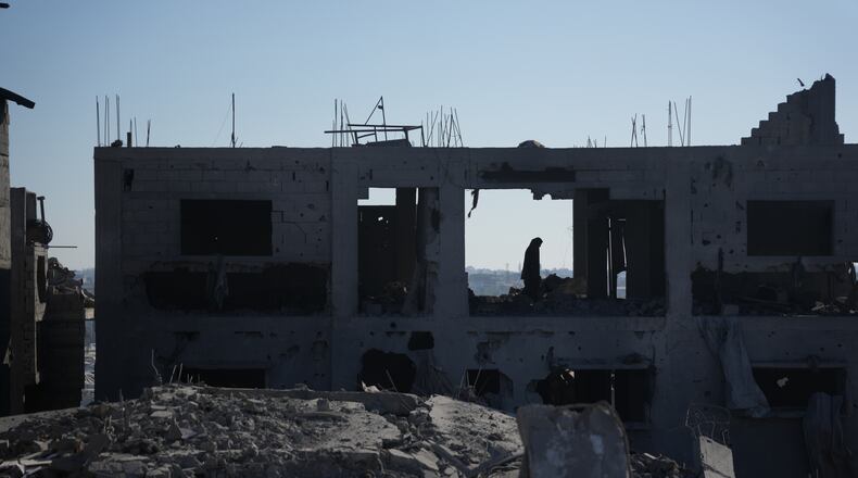 A Palestinian woman inspects a destroyed building following an Israeli airstrike in Deir al-Balah, central Gaza Strip, Sunday, July 19, 2026. (AP Photo/Abdel Kareem Hana)