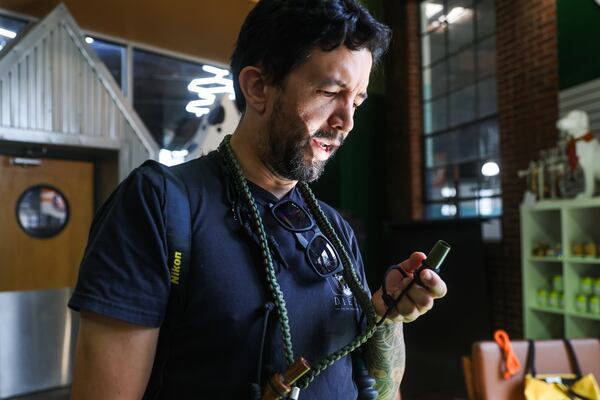 Photographer Diego Rodriguez talks about the whistles and tools he uses for photos at WAG-A-LOT Dog Daycare in Atlanta on Wednesday, Aug. 19, 2026. (Abbey Cutrer for the AJC)
