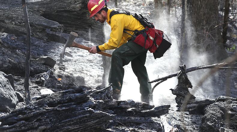 Firefighter Cody Henderson of New Mexico works on structure protection, putting out a hot spot above a home on the Tallulah River Road near the Georgia and North Carolina border while fighting the Rock Mountain Fire on Monday, Nov. 21, 2016, in Clayton.