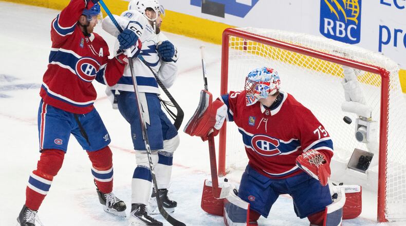 Tampa Bay Lightning's Brandon Hagel (38) scores past Montreal Canadiens goaltender Jakub Dobes (75) and Mike Matheson (8) during the third period of an NHL playoff hockey game, in Montreal, Sunday, April 26, 2026. (Christinne Muschi/The Canadian Press via AP)