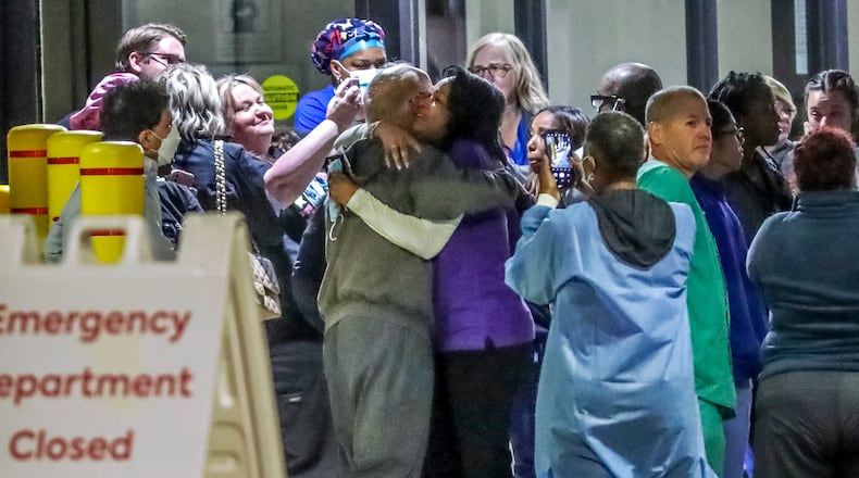 October 14, 2022 Atlanta: Medical workers embraced one another after closing Atlanta Medical Center’s emergency room. At about 5:30 a.m. Friday, Oct 14, 2022 the final patient to use Atlanta Medical Center’s emergency room walked out into downtown’s Old Fourth Ward neighborhood and turned onto Boulevard. At 7 a.m., staff locked the doors. A century of taking in patients had ended Hospital employees who weren’t even scheduled to work drove in to watch it happen, and found to their surprise that other co-workers had, too. Even past employees showed up. The president of AMC’s medical staff, Dr. Mark Waterman, was there. As workers ending a 12-hour overnight shift came outside in their scrubs and uniforms, they formed an impromptu goodbye ceremony. Waterman addressed them, thanking them for their service. They shared memories, especially of the impact they have had fighting the pandemic. The hospital will continue operating until its final closure on Nov. 1. AMC is approved for 460 beds, but recently only about 200 beds have been staffed with nurses. Many of AMC’s patients are less affluent than patients at other hospitals, with many lacking insurance, according to documents filed with the state and federal governments by Wellstar and other health systems. Finding new caregivers and medical facilities for those patients will be a challenge. (John Spink / John.Spink@ajc.com)