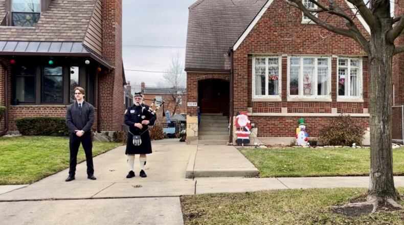 Chicago Police Department bagpiper Don McGrath bids farewell to Helen Gilligan Torpy outside her home as the funeral procession passes.