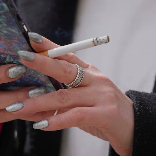 FILE - A woman smokes on a street in London on April 16, 2024. (AP Photo/Kin Cheung, File)