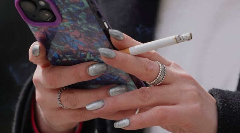 FILE - A woman smokes on a street in London on April 16, 2024. (AP Photo/Kin Cheung, File)