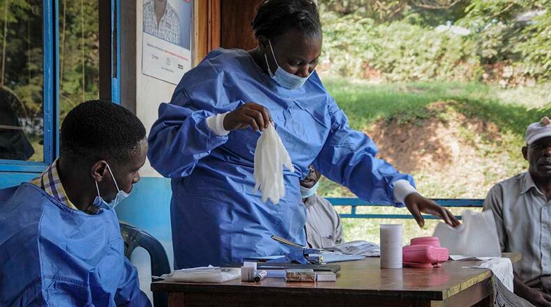 A health worker puts on protective clothing before vaccinating people against Ebola at the hospital in the village of Kagando, near the border with Congo, in June 2019. (AP Photo/Ronald Kabuubi)