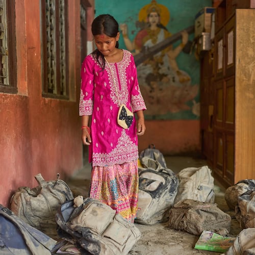 A student searches for her school bag from a pile extracted from the mud brought in by the recent flash floods, at the Shree Bagheswori Madhyamik School in Galchhi, Dhading district of Nepal Sunday, Aug. 30, 2026. (AP Photo/Niranjan Shrestha)