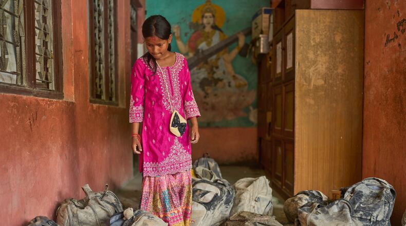 A student searches for her school bag from a pile extracted from the mud brought in by the recent flash floods, at the Shree Bagheswori Madhyamik School in Galchhi, Dhading district of Nepal Sunday, Aug. 30, 2026. (AP Photo/Niranjan Shrestha)