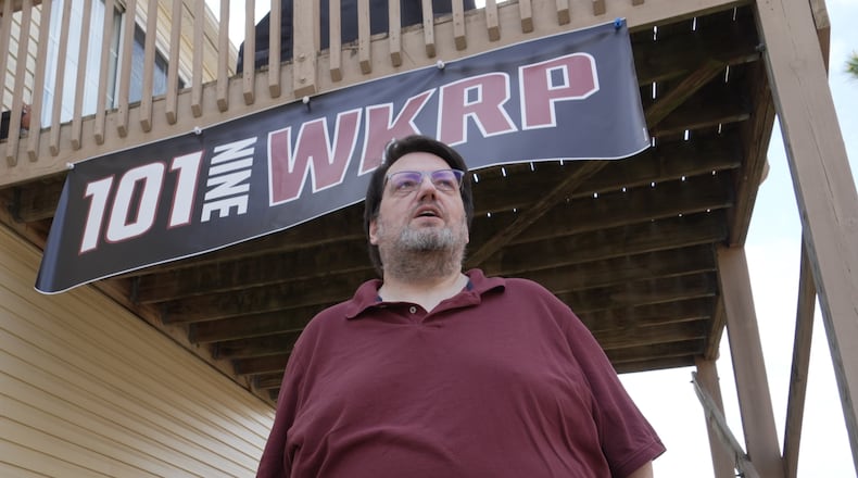 D.P. McIntire stands beneath a WKRP banner in the backyard of his home in Raleigh, N.C., on Thursday, April 2, 2026. (AP Photo/Allen G. Breed)