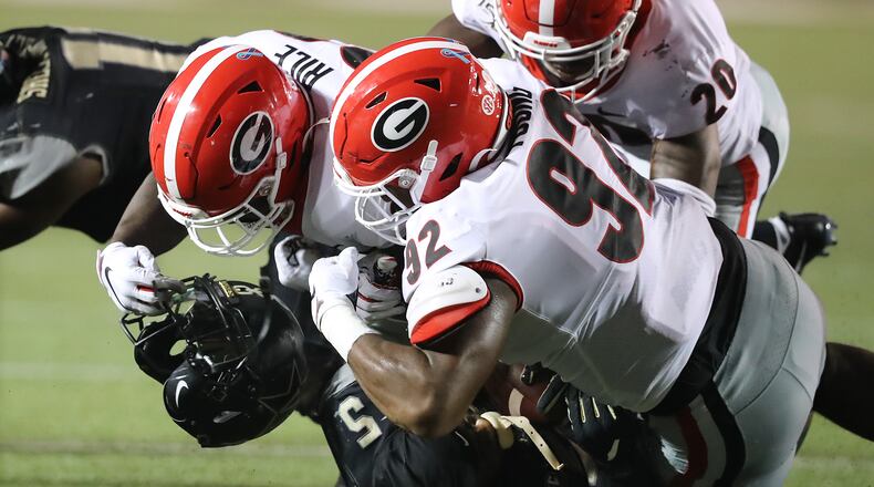 Georgia linebacker Monty Rice (L) ended up with Ke'Shawn Vaughn's helmet in his hand after he, Justin Young (92) and J.R. Reed gang-tackled Vanderbilt's star running back last Saturday. The Bulldogs will be looking for fewer penalties and more havoc in their home opener Saturday against Murray State. Curtis Compton/ccompton@ajc.com