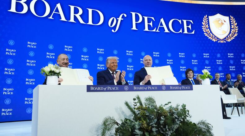 FILE - President Donald Trump, center, applauds as Ilham Aliyev, President of Azerbaijan, left, and Bulgaria's Prime Minister Rossen Jeliazkov, right, hold up their signed Board of Peace charter during the Annual Meeting of the World Economic Forum in Davos, Switzerland, Jan. 22, 2026. (AP Photo/Evan Vucci, File)