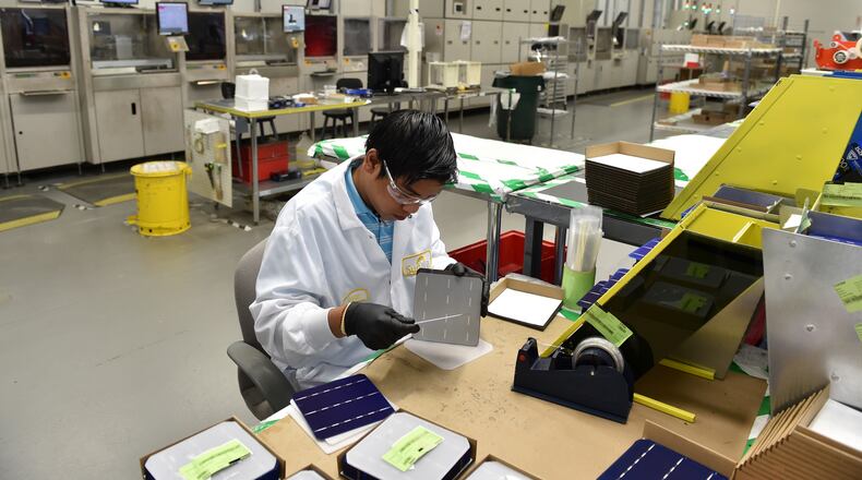 Norcross-based Suniva said it is cutting jobs after overseas competition and other challenges have hurt sales. Here, Nishan Kharga at Suniva’s Norcross factory performs a quality control inspection of solar cells before they are shipped out for assembly in solar panels. BRANT SANDERLIN /BSANDERLIN@AJC.COM