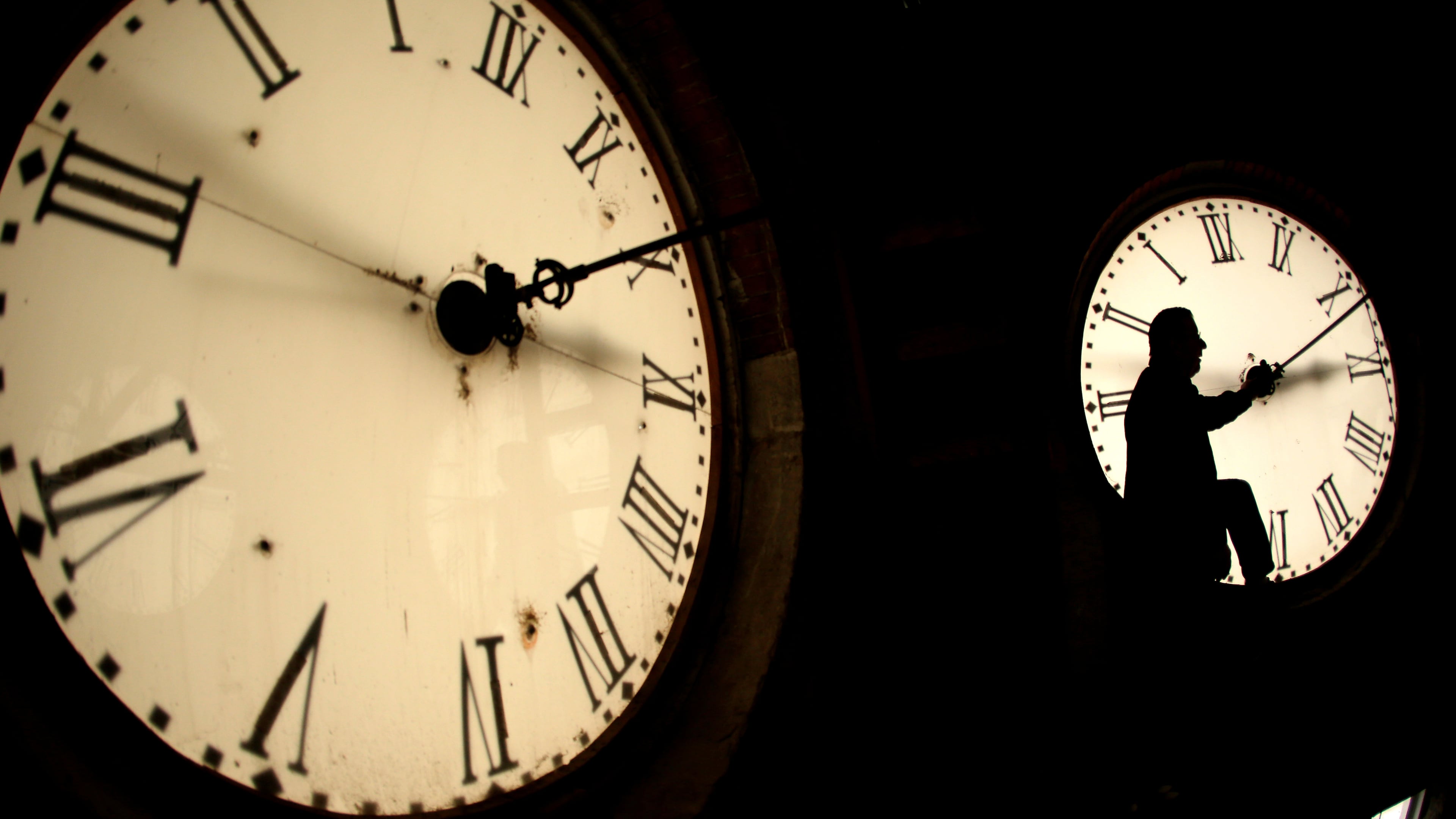 FILE - Custodian Ray Keen inspects a clock face before changing the time on the 100-year-old clock atop the Clay County Courthouse March 8, 2014, in Clay Center, Kan. (AP Photo/Charlie Riedel, File)