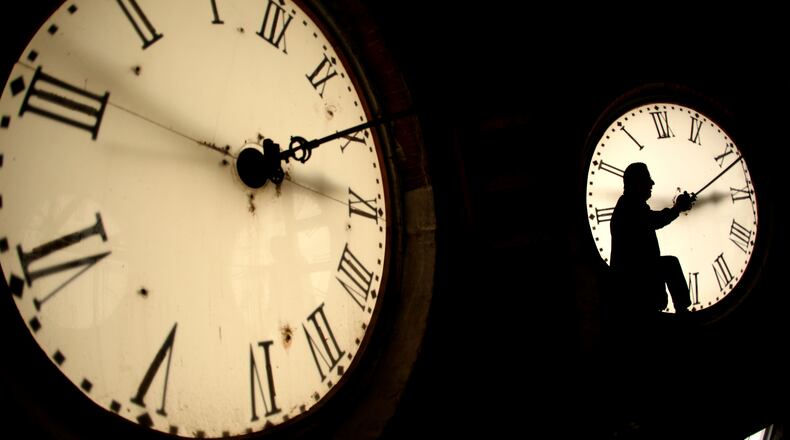 FILE - Custodian Ray Keen inspects a clock face before changing the time on the 100-year-old clock atop the Clay County Courthouse March 8, 2014, in Clay Center, Kan. (AP Photo/Charlie Riedel, File)