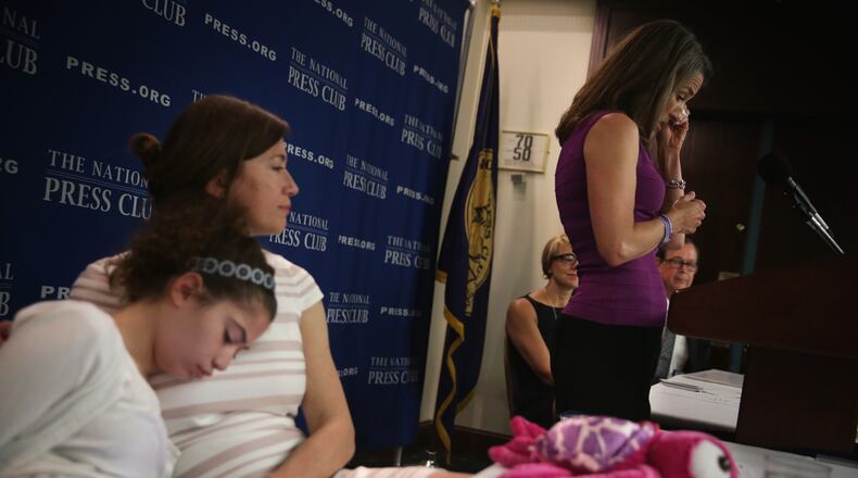 Liza Smith (R) of White Stone, Va., mother of 14-year-old Haley Smith (L) who suffers from a severe form of epilepsy called Dravet Syndrome, wipes tears as she speaks during a news conference about efforts to legalize therapeutic hemp and cannabidiol at the National Press Club April 22 in Washington. (Alex Wong/Getty Images)