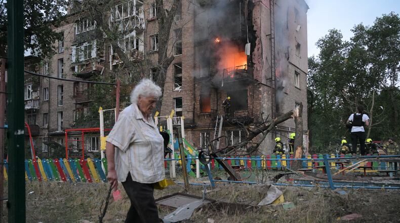A woman walks past a burning apartment building after a Russian missile attack in Kyiv, Ukraine, Thursday, July 2, 2026. (AP Photo/Danylo Antoniuk)