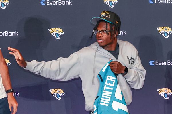 Two-way player Travis Hunter, the Jacksonville Jaguars first round draft pick, second overall, strikes a Heisman pose while holding a jersey during an NFL football press conference, Friday, April 25, 2025, in Jacksonville, Fla. (AP Photo/Gary McCullough)