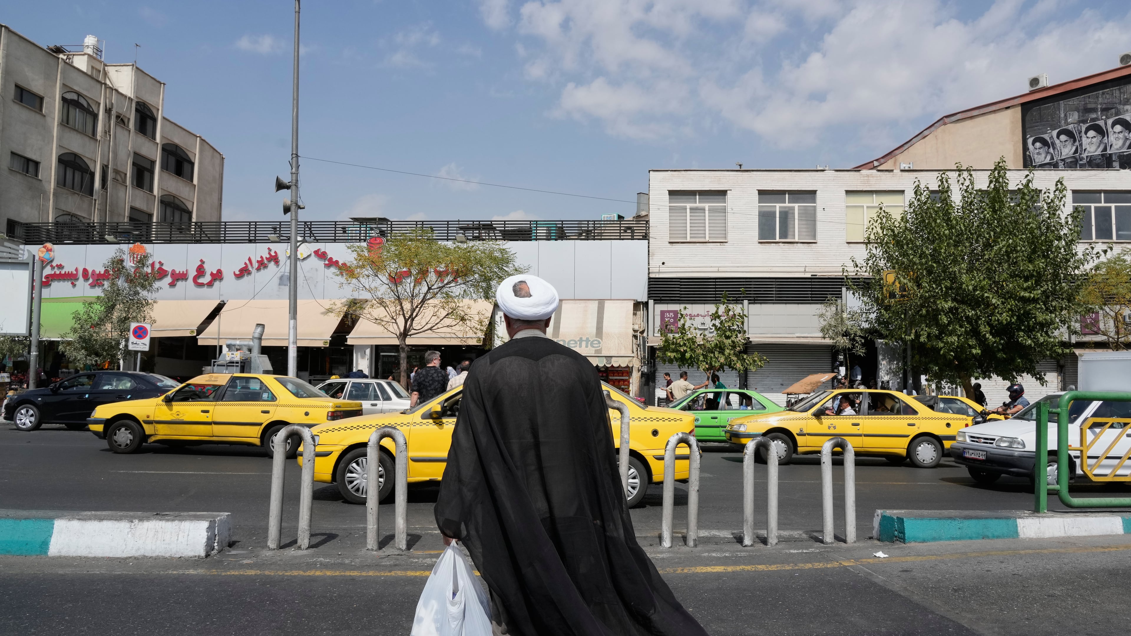 A cleric crosses the Enqelab-e-Eslami (Islamic Revolution) street, in Tehran, Iran, Saturday, Sept. 27, 2025. (AP Photo/Vahid Salemi)