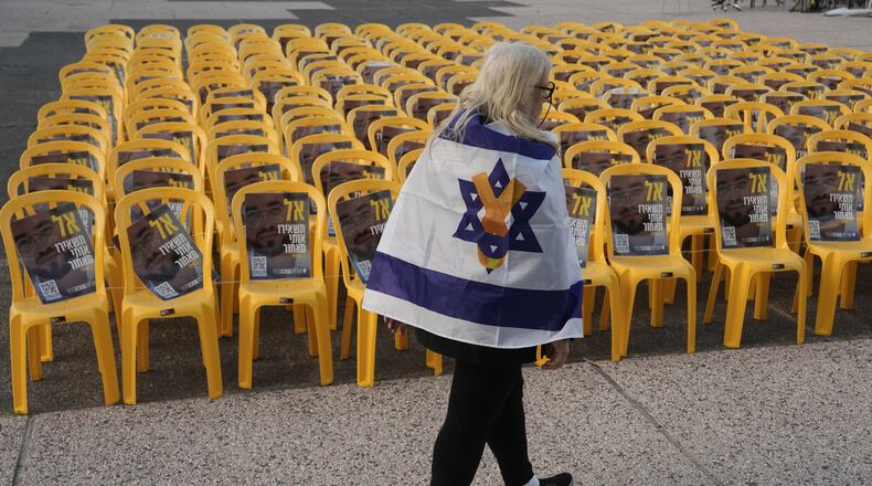 A woman walks by chairs with photos of Ran Gvili, the final hostage in Gaza who was killed while fighting Hamas militants during the Oct. 7, 2023 attack and whose remains have been recovered Monday, clearing the way for the next phase of the ceasefire that paused the Israel-Hamas war, in a plaza known as Hostages Square in Tel Aviv, Israel, Monday, Jan. 26, 2026. (AP Photo/Oded Balilty)