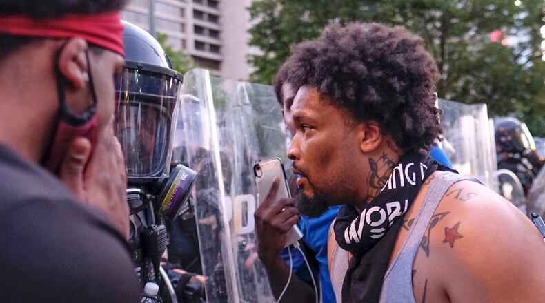 Demonstrators clash with Atlanta police officers in riot gear along Centennial Olympic Park Drive as protests over the death of George Floyd in Minneapolis in police custody continued Sunday for the third day.