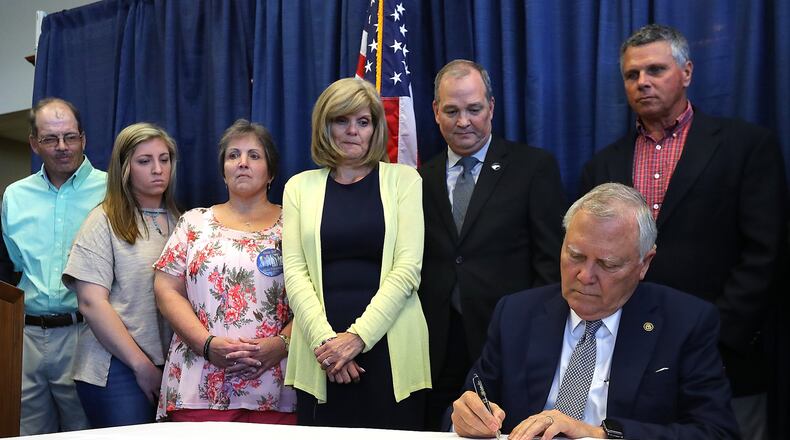 Gov. Nathan Deal signs House Bill 673 prohibiting Georgia motorists from handling their cellphones while driving as the families of five nursing students who died when they were struck by a semi on I-16 look on during a emotional ceremony at the Statesboro-Bullock County Airport on Tuesday, May 2, 2018, in Statesboro. Curtis Compton/ccompton@ajc.com