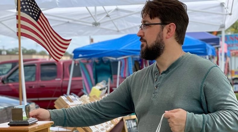 Joshua Hess, owner of the International City Farmers Market in Warner Robins, bags food for a customer. Hess used revenue from this business The Sassy Alpaca to purchase the market and help feed the homeless. (Photo Courtesy of Joshua Hess)