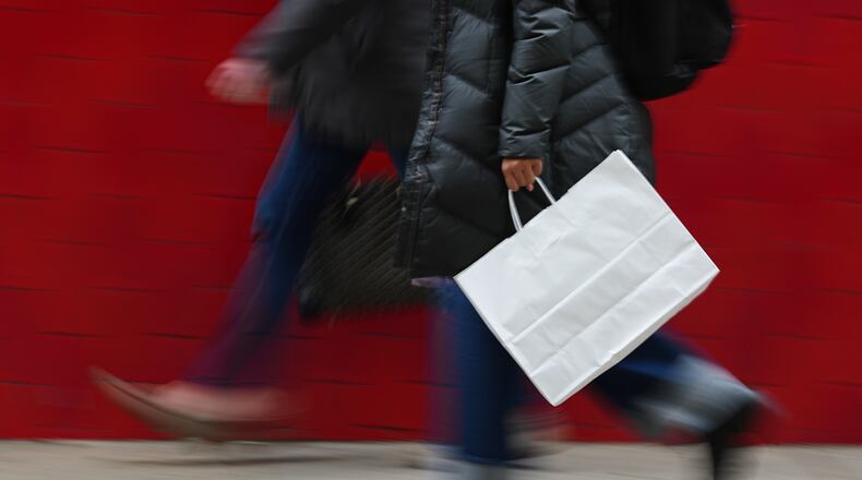 FILE - A person carries a shopping bag in Philadelphia, Dec. 10, 2025. (AP Photo/Matt Rourke, File)