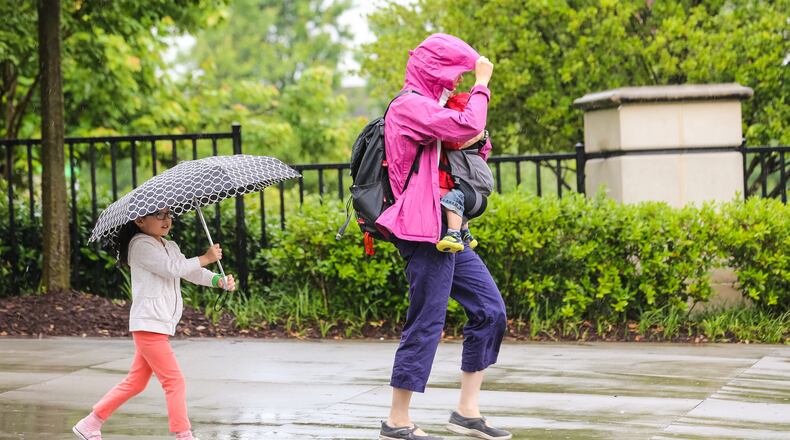 Karen Kee carries her 1-year-old toddler Harrison with her 4-year-old daughter Katie through the rain Tues., May 17, 2016 in downtown Atlanta. JOHN SPINK / JSPINK@AJC.COM