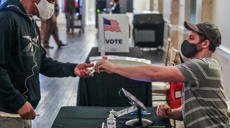 November 2, 2021 Atlanta: C.J. Andrews (right) checks in voters at Park Tavern located at 500 10th Street NE in Atlanta on Tuesday, Nov. 2, 2021. Normally, a wide-open vote for Atlanta mayor would take center stage in the metro area on Election Day. But low early turnout, a high number of undecided voters, and major competition for attention from Game Six of the World Series could scramble the outcome. Voting began Tuesday morning in elections for Atlanta mayor and city leaders across Georgia as voters hoped for short lines and no problems. Election Day will be closely watched in Fulton County, which covers most of the city of Atlanta. (John Spink / John.Spink@ajc.com)