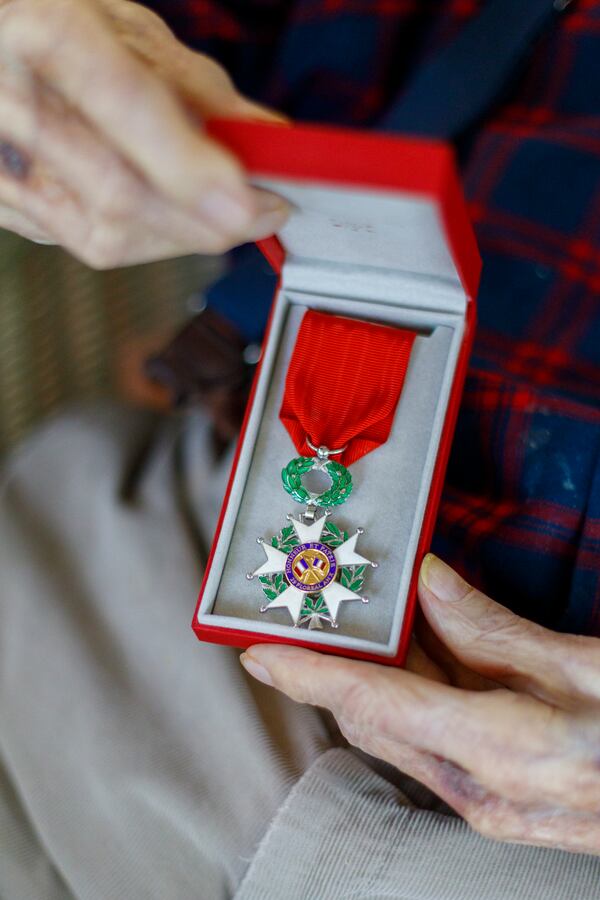 Avery Low, seated at his home in Savannah, shows the Legion of Honor awarded to him by France for his service in World War II. (Walker Smith for the AJC)
