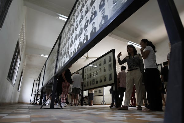 FILE - Tourists look at portraits of genocide victims in Khmer Rouge regime at the Tuol Sleng Genocide Museum, formerly the most notorious Khmer Rouge prison, in Phnom Penh, Cambodia, on July 10, 2014. (AP Photo/Heng Sinith, File)