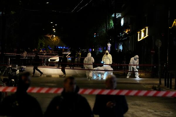 Police investigators wearing coveralls inspect the site after a bomb explosion outside of the Hellenic Train offices the company that runs Greece's railway, in Athens, Greece, Friday, April 11, 2025. (AP Photo/Petros Giannakouris)