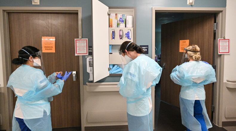 Nursing staff put on PPE before they attend to a COVID-19 patient at Memorial Health's Heart and Vascular Institute in Savannah on Thursday. (Hyosub Shin / Hyosub.Shin@ajc.com)