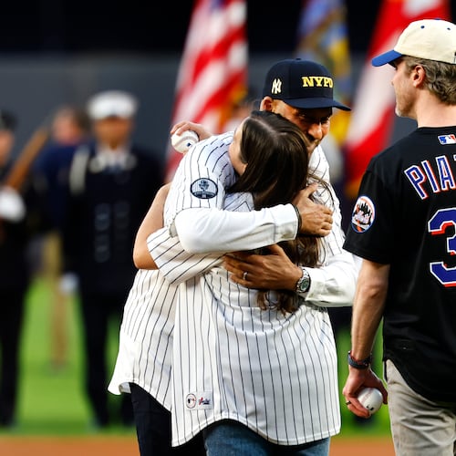 Derek Jeter hugs Brielle Saracini before she throws out the ceremonial first pitch with husband Sean McGuire before a baseball game between the New York Yankees and the New York Mets, Friday, Sept. 11, 2026, in New York. (AP Photo/Noah K. Murray)