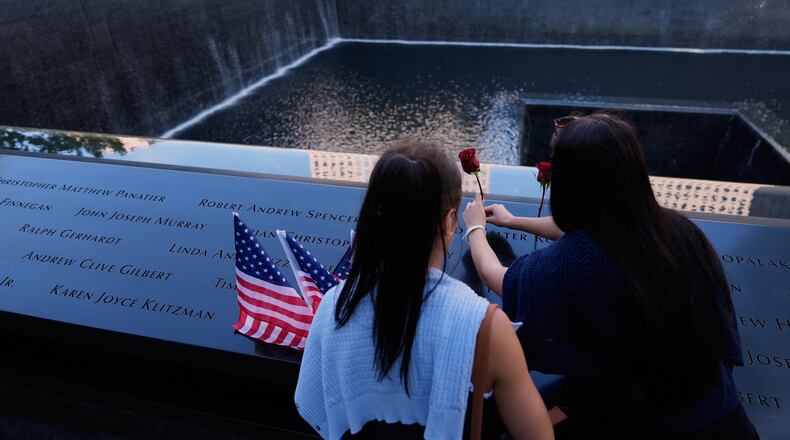 FILE - Ainsley, right, and Sarah Jurccak place a flower in the name of a relative during a ceremony to mark the 24th anniversary of the 9/11 attacks, Sept. 11, 2025, in New York. (AP Photo/Seth Wenig, File)