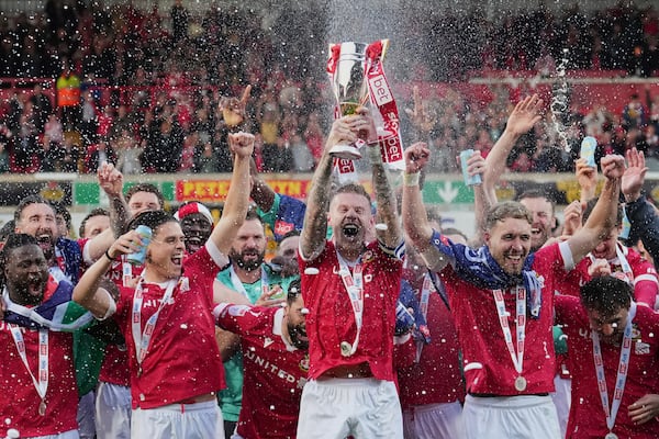 Wrexham's James McClean rises the trophy as they win the English League One soccer match between Wrexham and Charlton Athletic at the Racecourse ground in Wrexham, Wales, Saturday, April 26, 2025. (AP Photo/Jon Super)