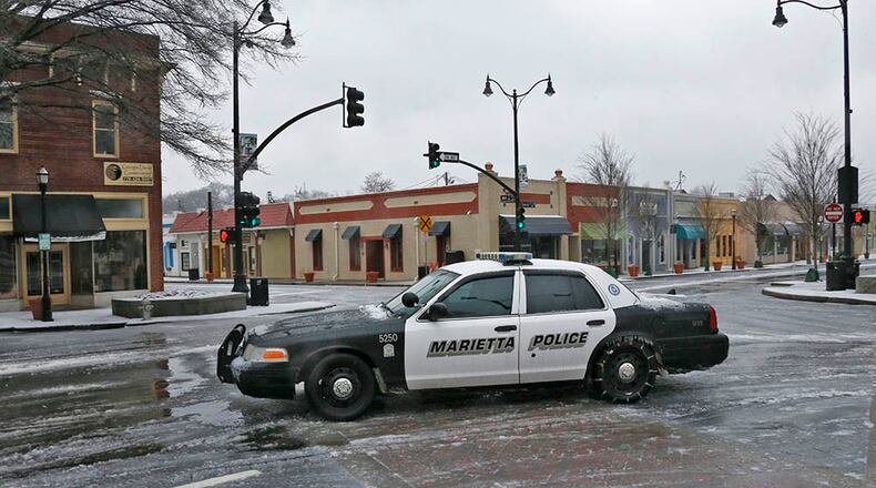 A Marietta Police car, outfitted with chains, cruises through the mostly deserted Marietta Square. Streets in Cobb County were mostly empty, and the square looked like a ghost town.