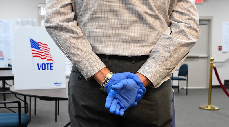 A poll worker wearing protective gloves waits to assist voters during special election voting at city hall to fill an empty city council seat on Tuesday, March 24, 2020, in Dacula. The voting happens to on a day that was supposed to be the test run for the state's new election system before coronavirus COVID-19 caused it to be called off.